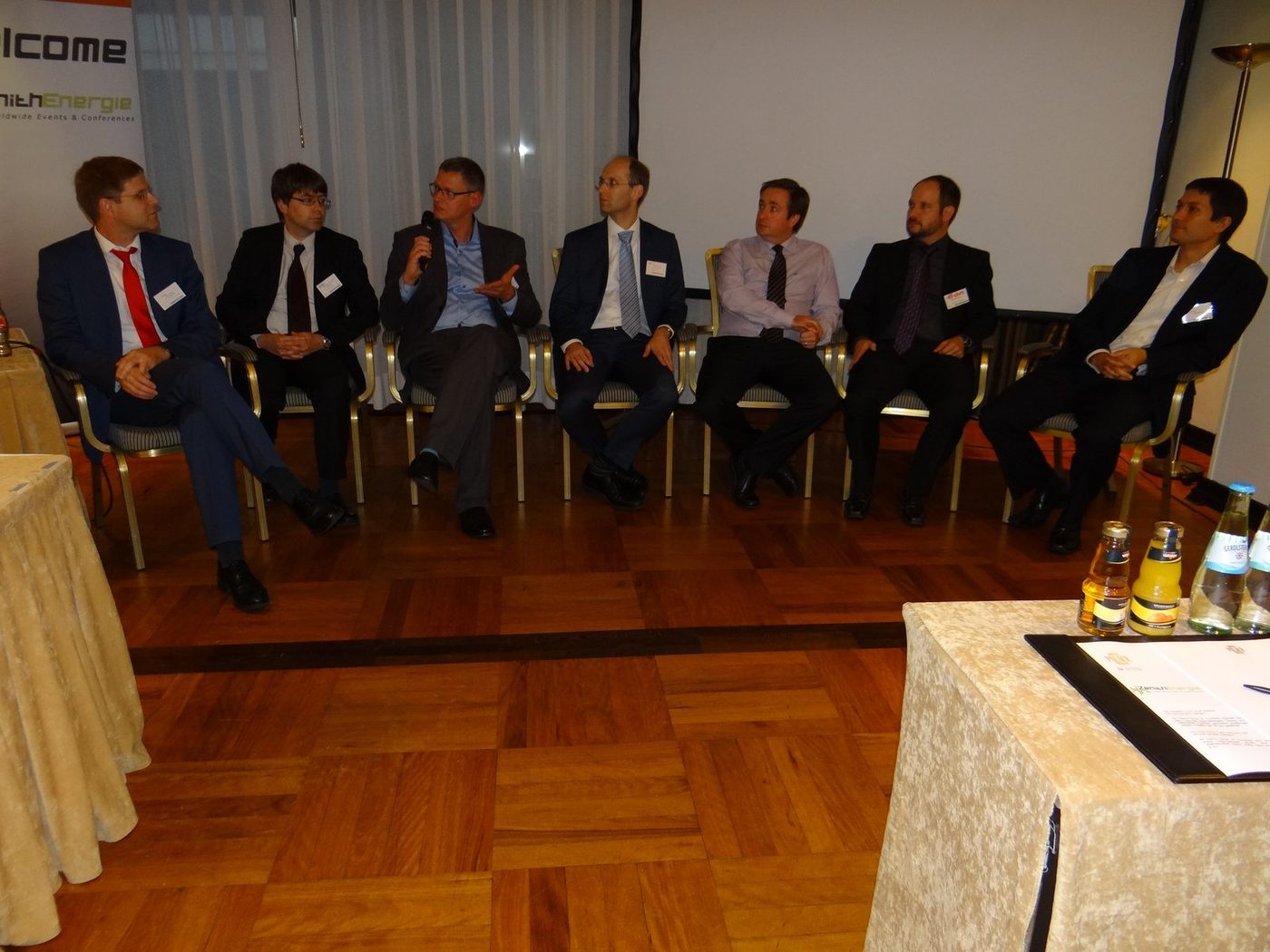 A panel on stage with a handheld microphone at a previous Zenith Group event